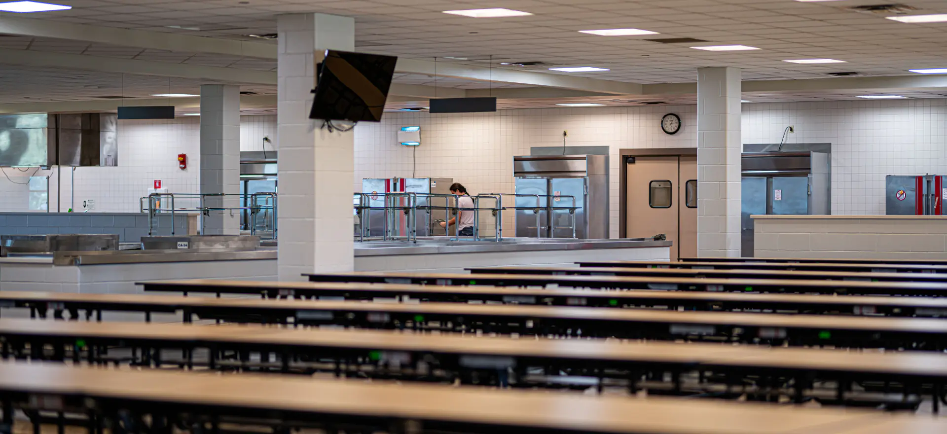 Modern school cafeteria with stainless steel serving stations and organized seating, representing public infrastructure.