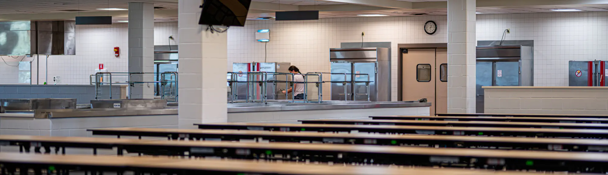 Modern school cafeteria with stainless steel serving stations and organized seating, representing public infrastructure.