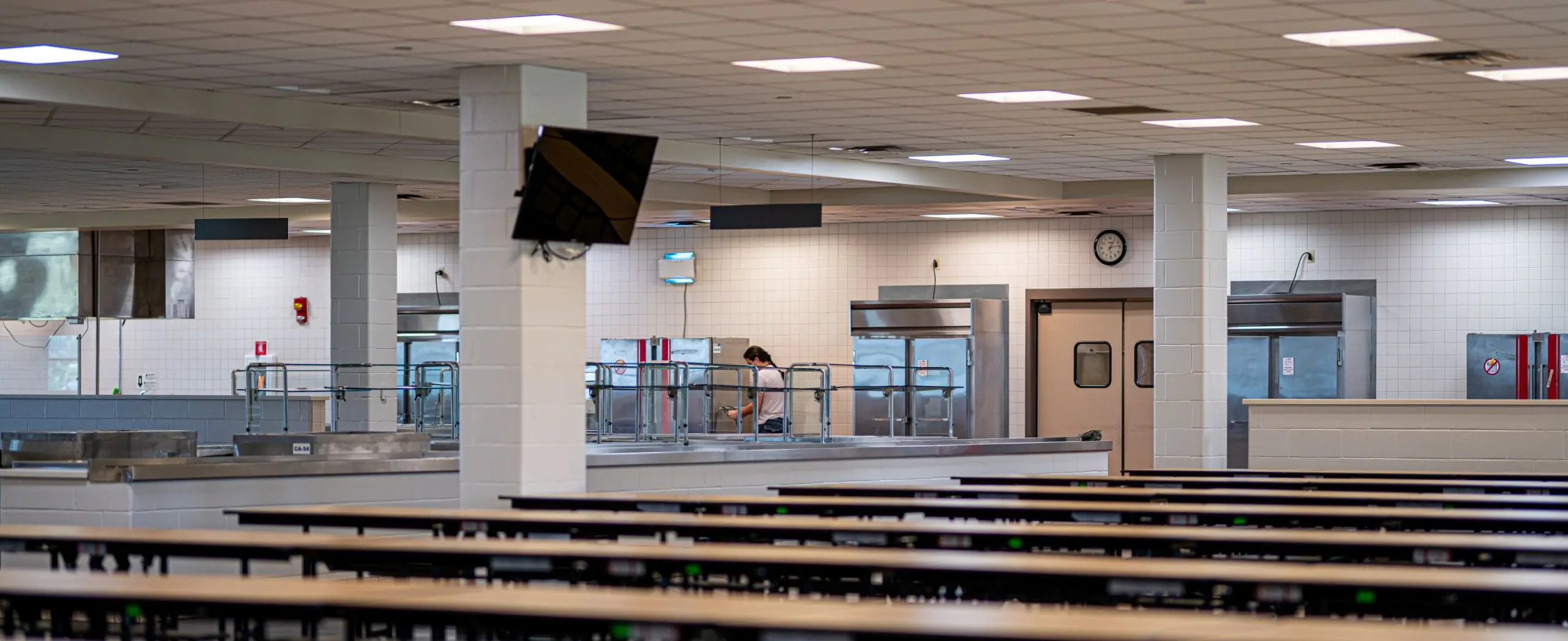 Modern school cafeteria with stainless steel serving stations and organized seating, representing public infrastructure.
