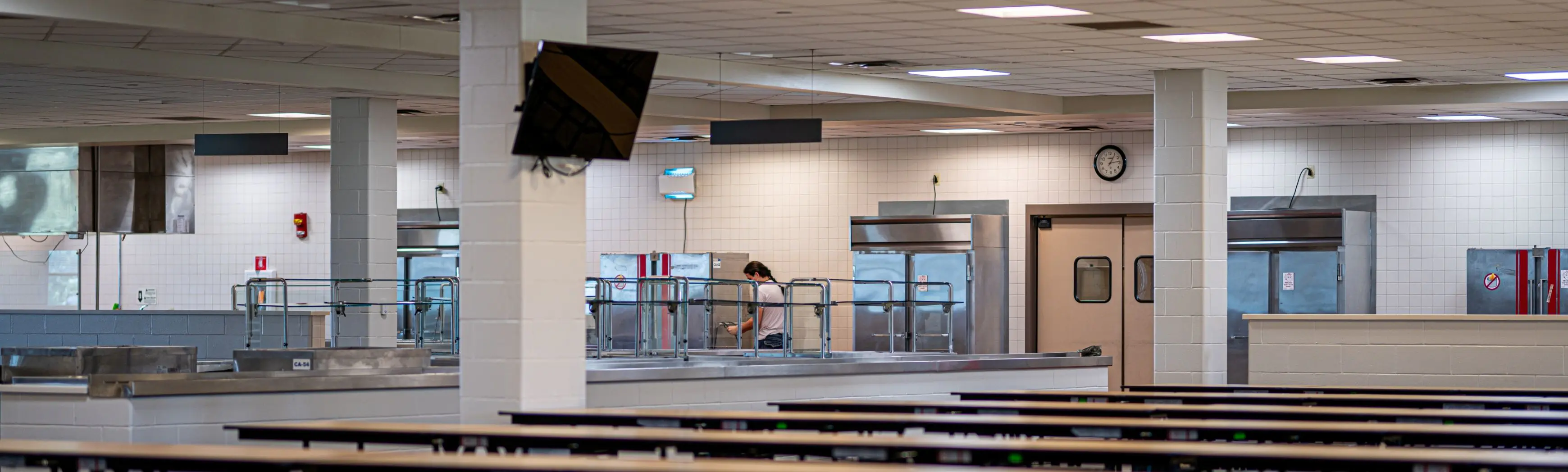 Modern school cafeteria with stainless steel serving stations and organized seating, representing public infrastructure.