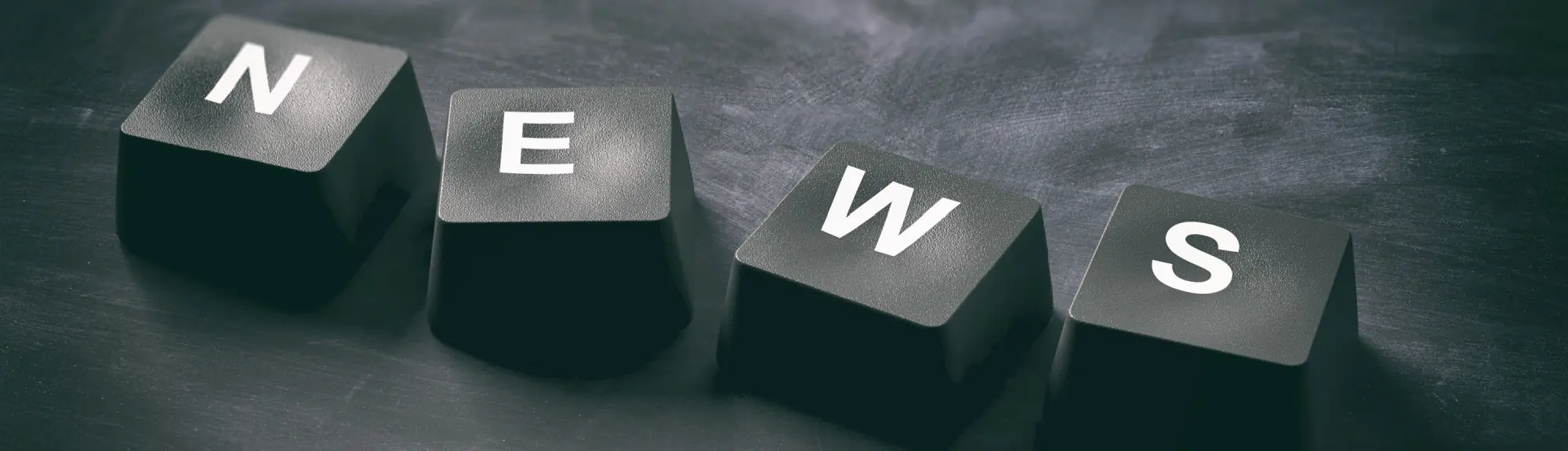 Black keyboard keys spelling “NEWS” on a dark surface, representing digital updates and public communication.