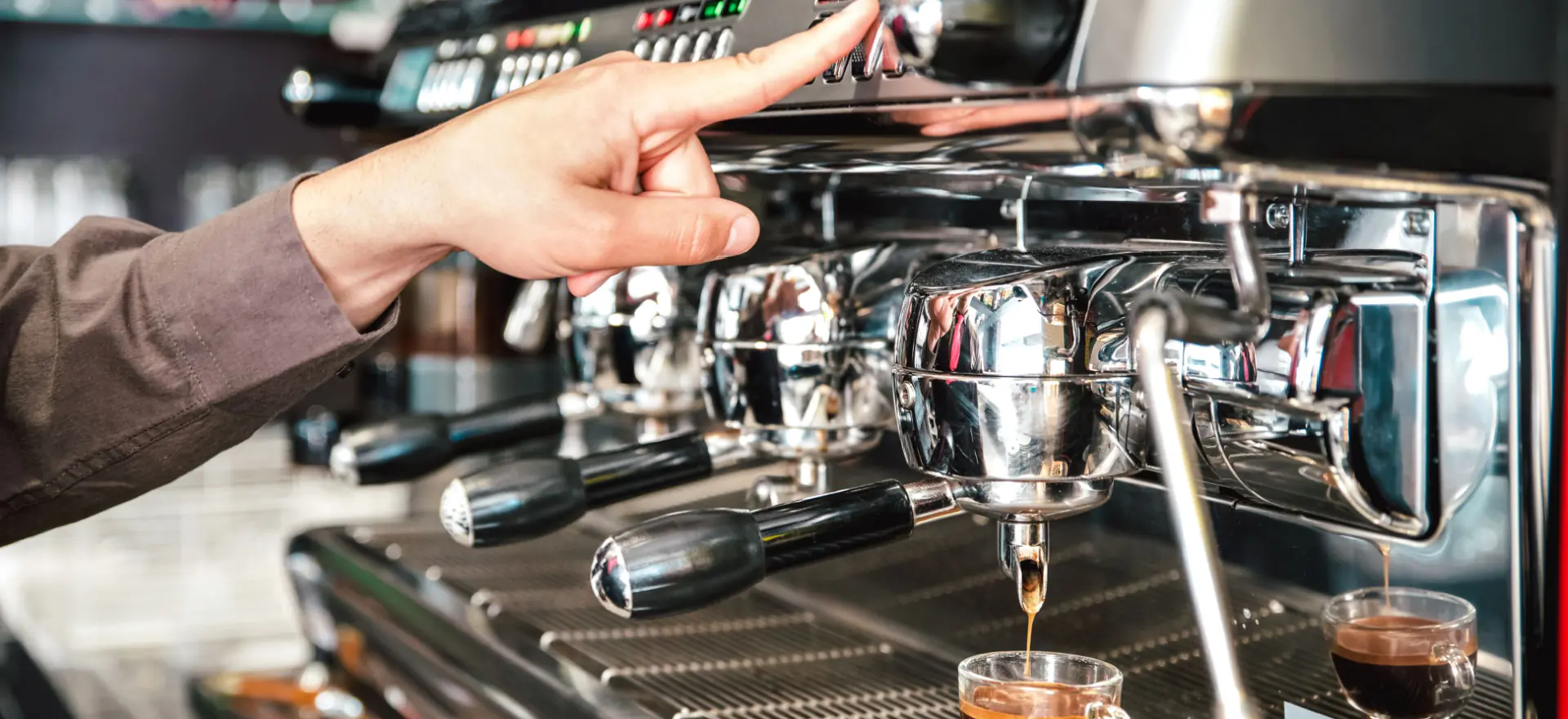 Commercial espresso machine dispensing coffee into glass cup in professional setting.