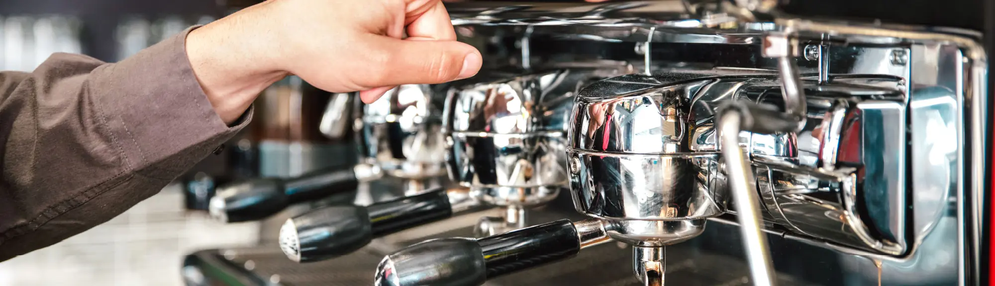 Commercial espresso machine dispensing coffee into glass cup in professional setting.